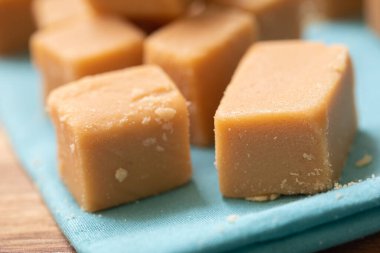 Tahta bir tahtanın üzerinde küp şeklinde Dulce de leche ve görüntünün kompozisyonu peçete. Brezilya yemeği, tatlı..