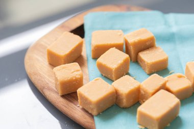 Tahta bir tahtanın üzerinde küp şeklinde Dulce de leche ve görüntünün kompozisyonu peçete. Brezilya yemeği, tatlı..