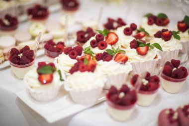 Taze çilek, ahududu ve nane yaprağıyla nefis bir pasta. Meyve ve böğürtlen dolu bir ziyafet masası ve bir sürü tatlı. Şeker çubuğu.