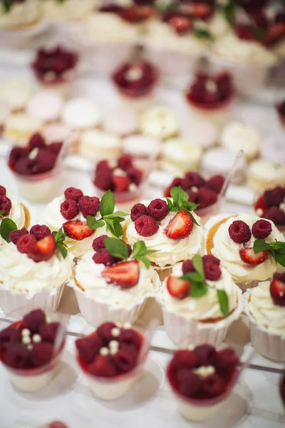 Taze çilek, ahududu ve nane yaprağıyla nefis bir pasta. Meyve ve böğürtlen dolu bir ziyafet masası ve bir sürü tatlı. Şeker çubuğu.