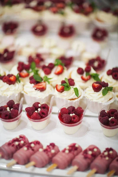 Taze çilek, ahududu ve nane yaprağıyla nefis bir pasta. Meyve ve böğürtlen dolu bir ziyafet masası ve bir sürü tatlı. Şeker çubuğu.