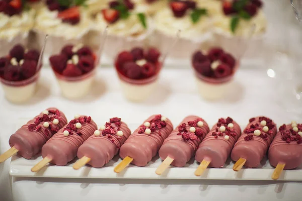 Taze çilek, ahududu ve nane yaprağıyla nefis bir pasta. Meyve ve böğürtlen dolu bir ziyafet masası ve bir sürü tatlı. Şeker çubuğu.