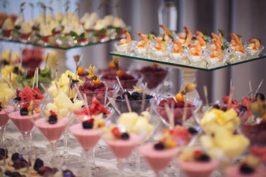 Catering on wedding. Wedding banquet table. Sweet table with fruit. Fruit bar on party. Delicious fruits appetizers. Tasty desserts, cakes and pastry on the wedding sweet buffet.
