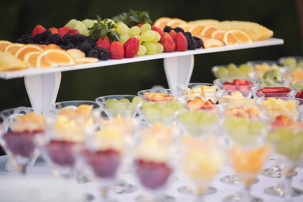 Catering on wedding. Wedding banquet table. Sweet table with fruit. Fruit bar on party. Delicious fruits appetizers, desserts on stand, modern sweet tab.