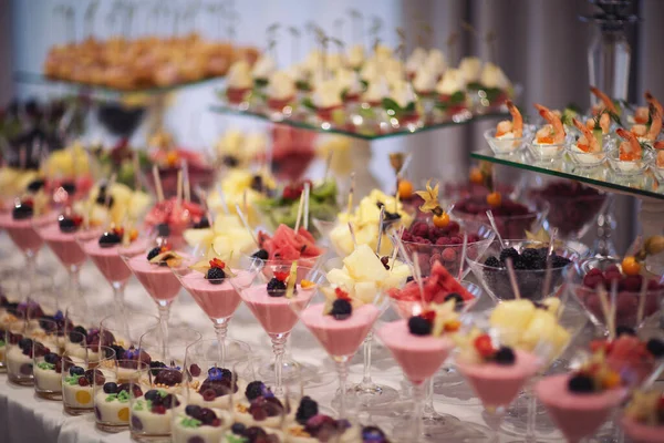 Catering on wedding. Wedding banquet table. Sweet table with fruit. Fruit bar on party. Delicious fruits appetizers. Tasty desserts, cakes and pastry on the wedding sweet buffet.