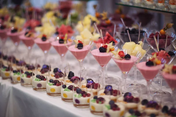 Catering on wedding. Wedding banquet table. Sweet table with fruit. Fruit bar on party. Delicious fruits appetizers. Tasty desserts, cakes and pastry on the wedding sweet buffet.