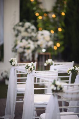 Wedding Florals at a vineyard for a summer wedding aisle ceremony with white chairs. floral decor of white wedding chairs for guests.