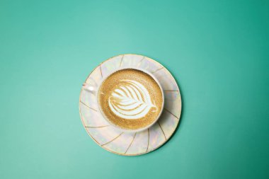 Turkuaz arka planda kahve ve kremalı bir fincan.
