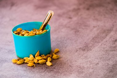 Siyah arka planda yeşil kakule tohumları ve seçici odaklı mavi bardak.,