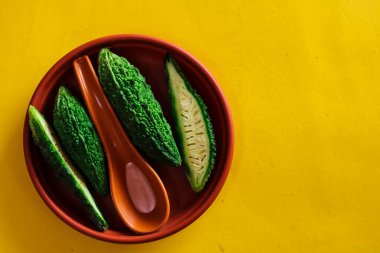 Karela parlak sarı arka planda parçalara ayrıldı, Momordica Charantia, sarı arka planda vahşi acı kabak, acı salatalığı kapat,