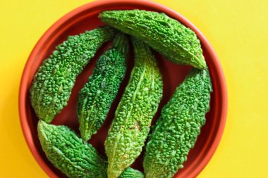 Karela parlak sarı arka planda parçalara ayrıldı, Momordica Charantia, sarı arka planda vahşi acı kabak, acı salatalığı kapat,