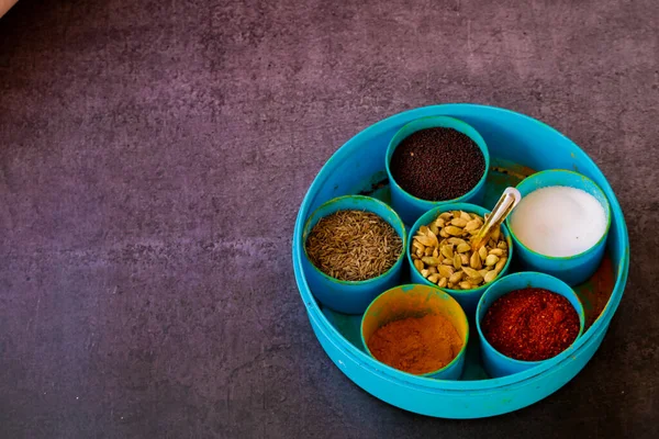 Essential Indian spices in an Indian spice box with copy space background,Cardamom, turmeric, chilli powder, salt,mustard seeds,cumin, selective focus