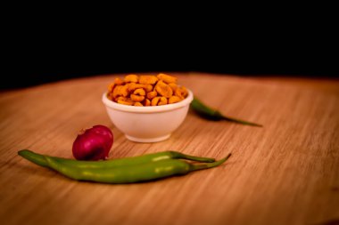 Masala ya da baharatlı Çin yemeği çok popüler bir Gujarati aperatifi, beyaz kase, masala atan Namkeen ya da ahşap masada kavrulmuş baharatlı fıstık ve soğan ve yeşil biber.