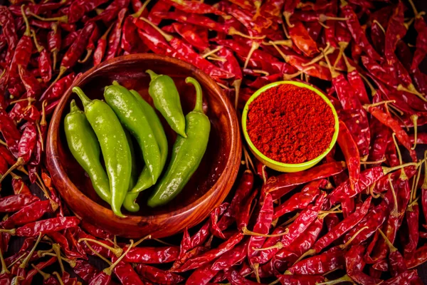 Dried chili pepper in wooden bowl on the wooden table with Chili pepper powder in yellow Bowl,used as hot spice,