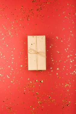 Kırmızı arka planda küçük parıltıları olan bir hediye. Bayramlar için şenlik arkaplanı, doğum günü, sevgililer günü, Noel, yeni yıl. Düz yatıyordu.