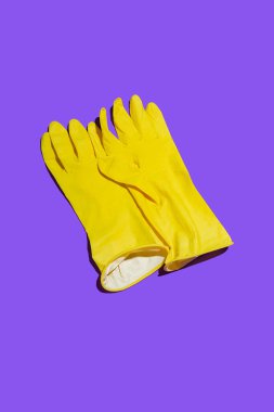 Mor ve mavi arka planda büyük sarı lastik eldivenler. Yukarıdan görüntüle.