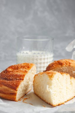 Gri arka planda şekerli kalp şeklinde taze pişmiş beyaz ekmek. Yanında bir bardak süt var..