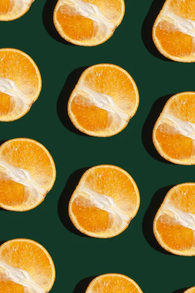 Tasty healthy orange cut pattern on a trendy green background. View from above.