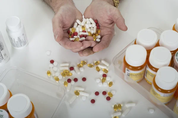 Mãos segurando pílulas cercadas por garrafas de pílula — Fotografia de Stock