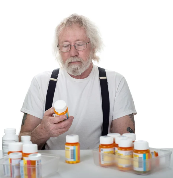 Senior kijkend naar een fles pillen — Stockfoto