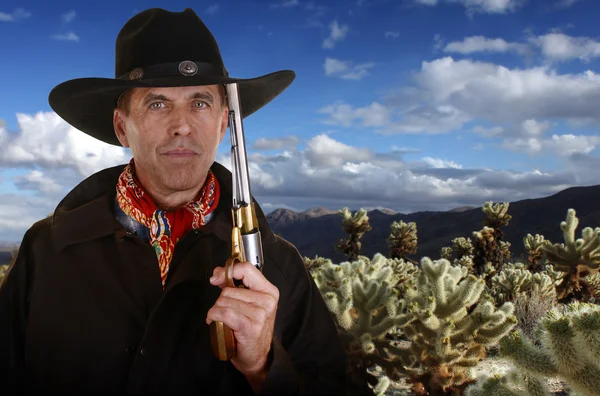 Cowboy with gun touching hat in cholla garden — Stock Photo, Image