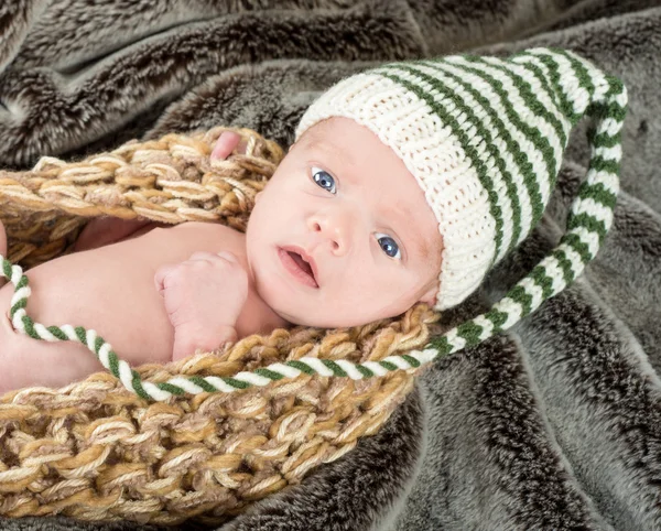 Recém-nascido de olhos azuis adorável em uma cesta de malha com um verde e whi — Fotografia de Stock
