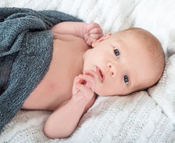 Mooie wakker baby liggend op een witte brei deken — Stockfoto