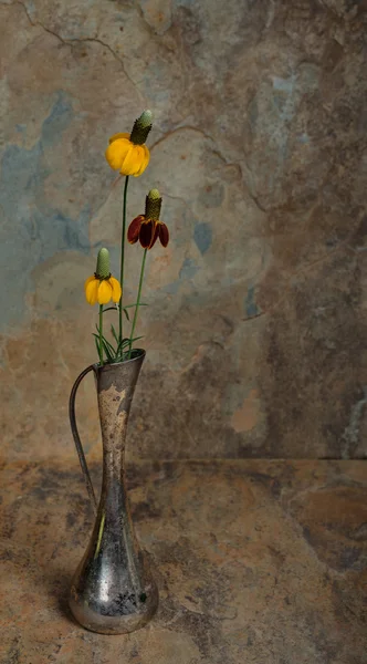 Дикие цветы в антикварной серебряной вазе с шиферным фоном — стоковое фото