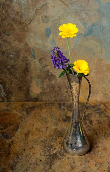 Flores silvestres púrpuras y amarillas en un florero de plata antiguo en una sla — Foto de Stock