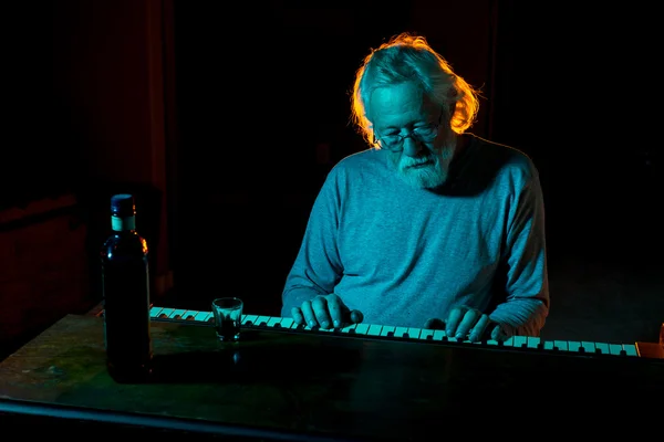 Homem sênior tocando um piano velho enquanto bebe álcool — Fotografia de Stock