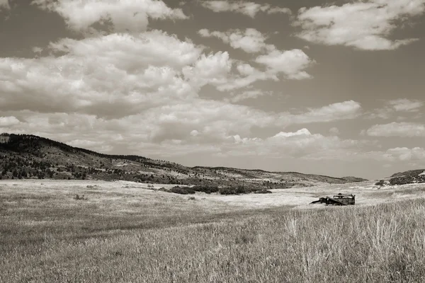 Abandoned wheat fied with old farm equipment in sepia — Stock Photo, Image