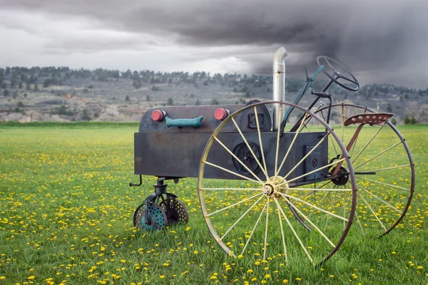 Unusual antique tractor in a meadow of dandelions with a stormy — Stock Photo, Image