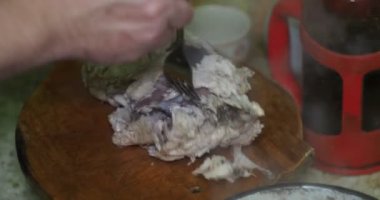 Asya mutfağı. Aşçı haşlanmış tavuk etini haşlanmış et suyuyla tencereden çıkarır ve onları kesme tahtasına koyar. Yakın plan..