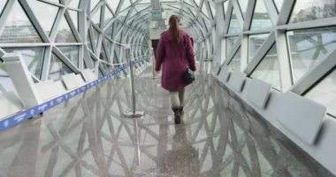 Güvenlik sistemi. Yüzünde tıbbi maske olan genç bir kadın teftiş kapısının önünde uzun bir koridorda yürüyor..