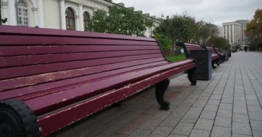 Şehre. Şehir parkındaki kaldırımda kaldırım levhalarıyla kaplı uzun bir sıra boş bank. Moskova.