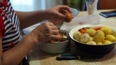 Asya mutfağı, basit yiyecekler. Yumurtayı temizleyen ve kabuğunu bir fincan haşlanmış patatesin yanına koyan bir kadının elleri. Yakın plan..