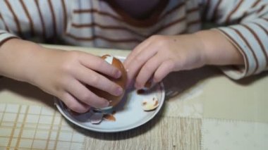 Çocuklar işte. Haşlanmış yumurtanın kabuğunu ilk defa soymaya çalışan küçük bir çocuğun elleri. Yakın plan..
