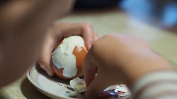 子供たち 初めてゆで卵から殻をはぎ取ろうとしている小さな子供の手 — ストック動画