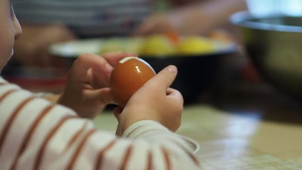 子供たち 初めてゆで卵から殻をはぎ取ろうとしている小さな子供の手 — ストック動画