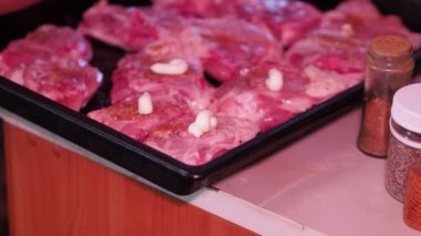 Asya mutfağı. Aşçı fırın tepsisine uzanmış tavuk parçalarına mayonez serer. Yakın plan..