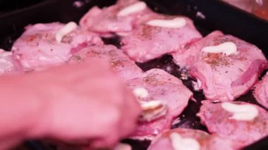 Asya mutfağı. Aşçı fırın tepsisine uzanmış tavuk parçalarına mayonez serer. Yakın plan..