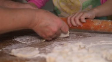Asya mutfağı. Çocuk mutfaktadır. Küçük bir kıza hamurdan un yapmayı öğreten yaşlı bir kadının elleri. Sibirya.