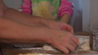 Asya mutfağı. Çocuk mutfaktadır. Küçük bir kıza hamurdan un yapmayı öğreten yaşlı bir kadının elleri. Sibirya.