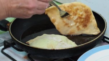 Asya mutfağı. Aşçı kızartma tavasında yağda kızartılmış turtaları çevirir..