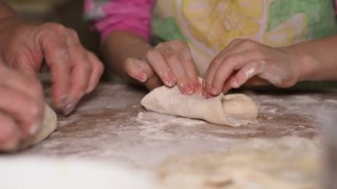 Asya mutfağı. Çocuk mutfaktadır. Küçük bir kıza hamurdan un yapmayı öğreten yaşlı bir kadının elleri. Sibirya.