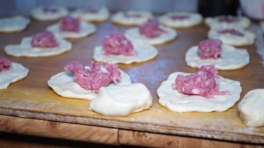 Asya mutfağı. Yaşlı bir kadın turtaları etle doldurur ve kızartma tavasında yağda kızartmak için özel olarak sarar. Sibirya 'da. Yakın çekim..