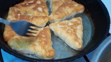 Asya mutfağı. Aşçı kızartma tavasında sebze ve etle doldurulmuş turta (belyashi) pişiriyor. Sibirya 'da. Yakın çekim..