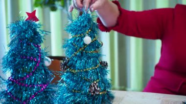 Tatil sezonu. Mutlu yaşlı bir kadın bayram için küçük bir Noel ağacı süsler. Yakın plan..