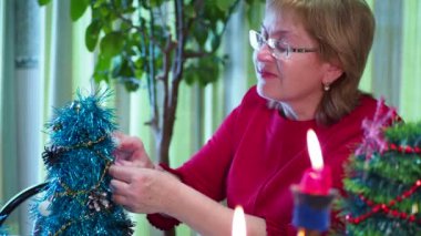 Tatil sezonu. Mutlu yaşlı bir kadın bayram için küçük bir Noel ağacı süsler. Yakın plan..