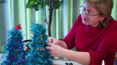 Tatil sezonu. Mutlu yaşlı bir kadın bayram için küçük bir Noel ağacı süsler. Yakın plan..